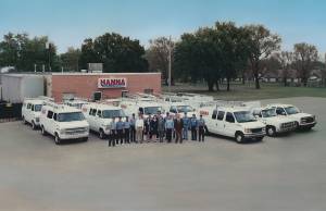 Photo from the 1970s of Hanna Inc and its large staff standing in front of 2 long rows of hvac trucks and vans at the Wichita location