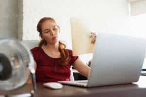 Businesswoman Sweating At Work With a Broken Air Conditioner is blowing hot air