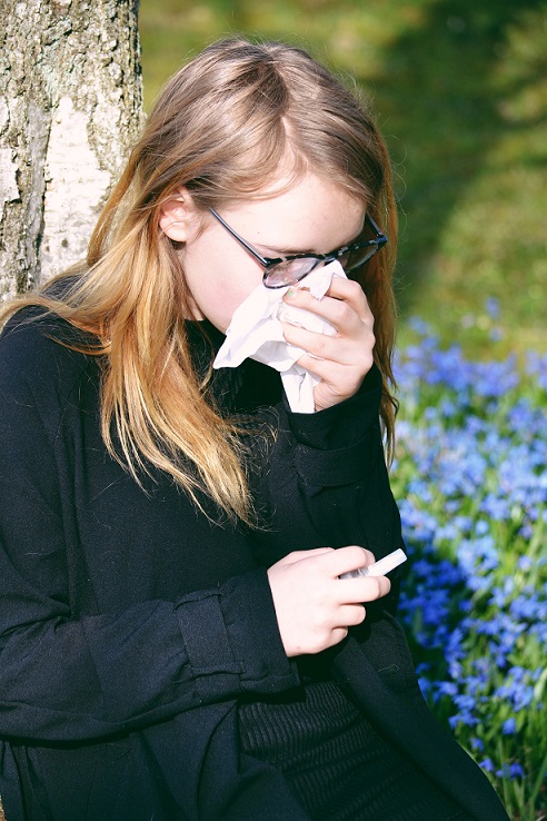 Girl outside with tissue suffering with allergies in Kansas