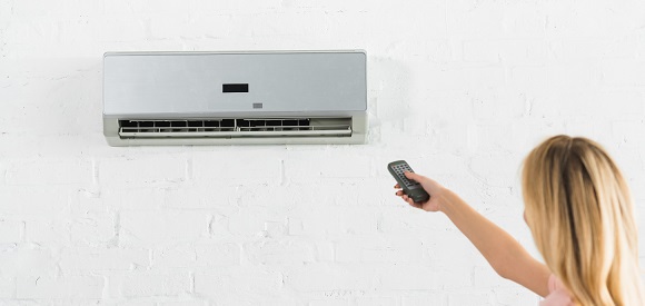 Woman changing setting on a mini split system for cooling a home office