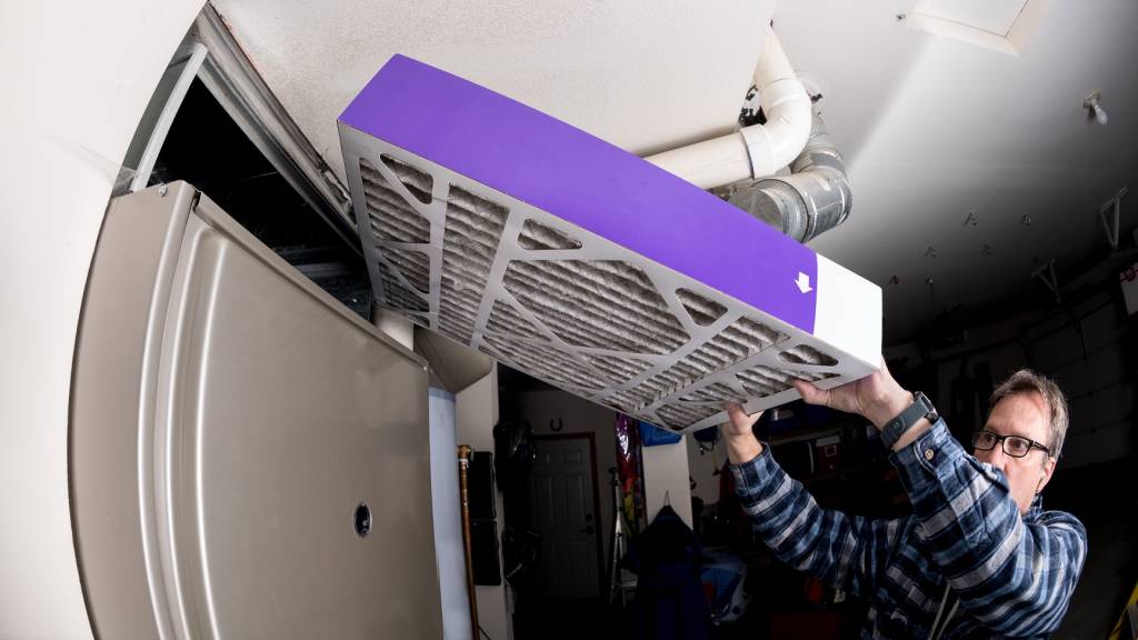 Guy installing a pleated air filter in furnace